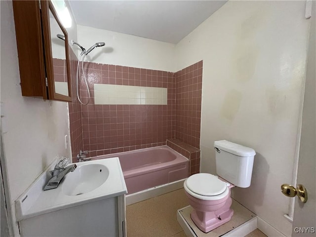 full bathroom featuring tiled shower / bath, vanity, and toilet