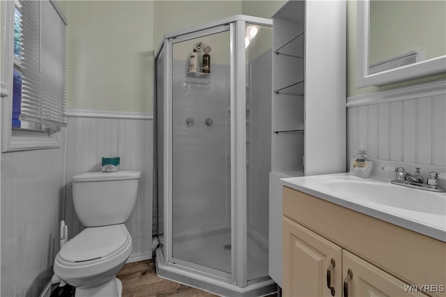 bathroom featuring vanity, toilet, hardwood / wood-style flooring, and a shower with door