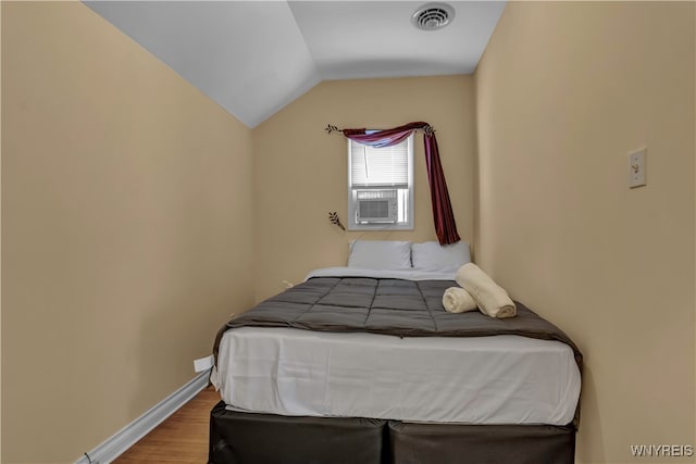 bedroom with lofted ceiling, hardwood / wood-style flooring, and cooling unit