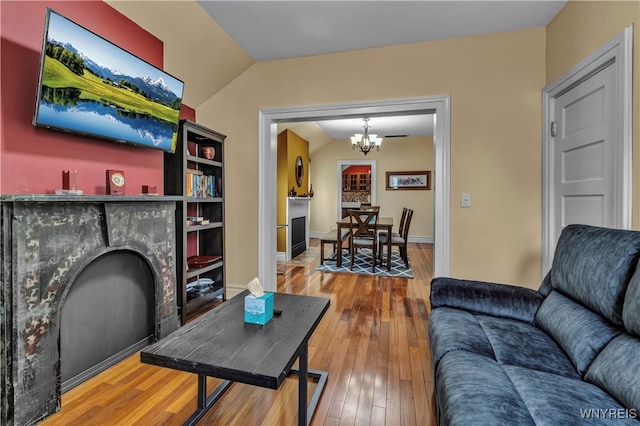 living room with hardwood / wood-style flooring, vaulted ceiling, and an inviting chandelier