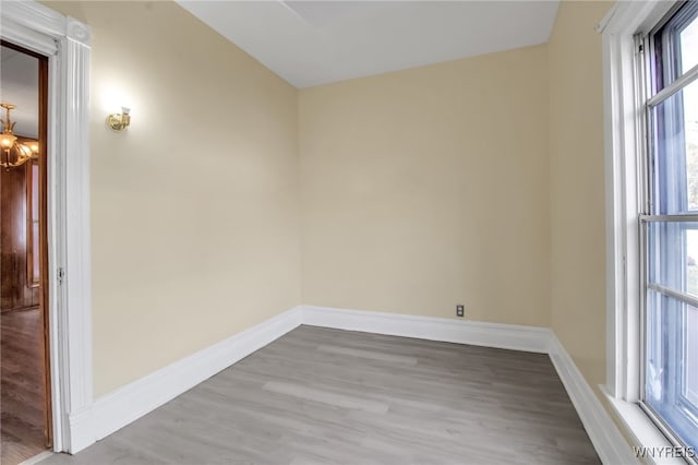 spare room with light hardwood / wood-style floors, a notable chandelier, and plenty of natural light