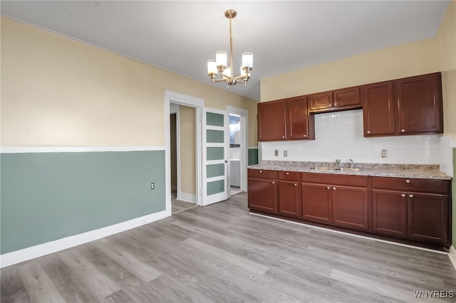 kitchen with pendant lighting, an inviting chandelier, light wood-type flooring, and sink