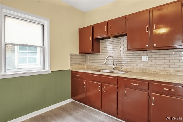 kitchen with wood walls, sink, and light wood-type flooring