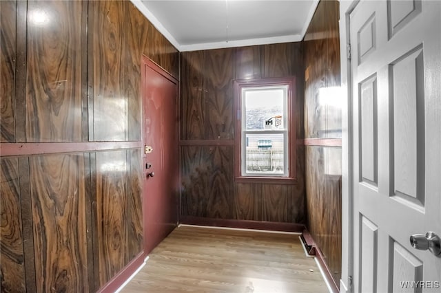 entryway featuring wood walls, ornamental molding, and light hardwood / wood-style flooring