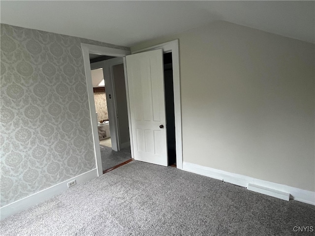 unfurnished bedroom with a closet, carpet flooring, and lofted ceiling