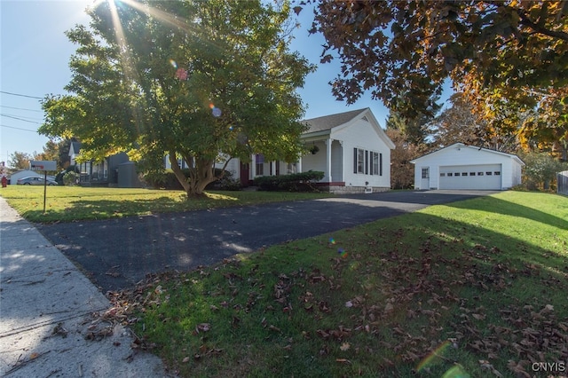 view of property hidden behind natural elements featuring a front yard, an outdoor structure, and a garage