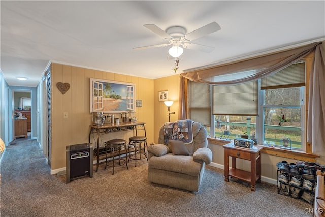 living area with ornamental molding, carpet flooring, and ceiling fan