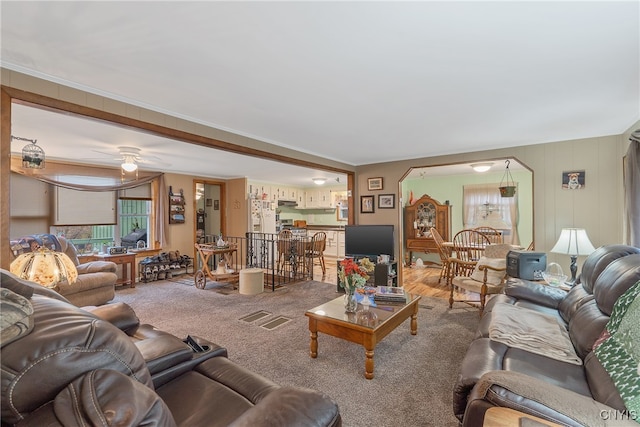 carpeted living room featuring ornamental molding and ceiling fan