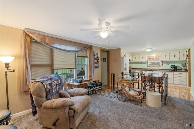 carpeted living room featuring crown molding and ceiling fan