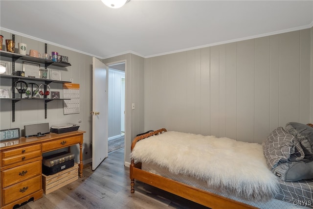 bedroom featuring crown molding, light wood-type flooring, and wooden walls