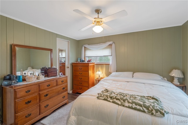 bedroom with ceiling fan, ornamental molding, and wooden walls