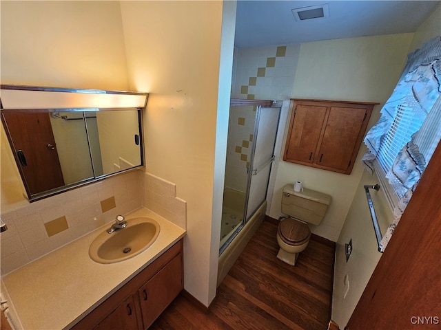 bathroom with decorative backsplash, toilet, hardwood / wood-style floors, vanity, and an enclosed shower