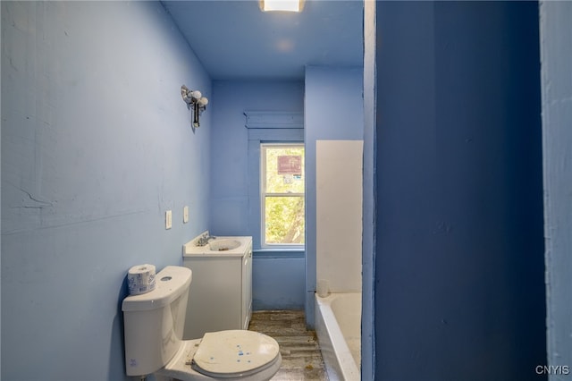 bathroom with hardwood / wood-style floors, vanity, a tub, and toilet