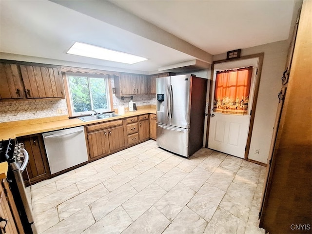 kitchen featuring sink, appliances with stainless steel finishes, and tasteful backsplash