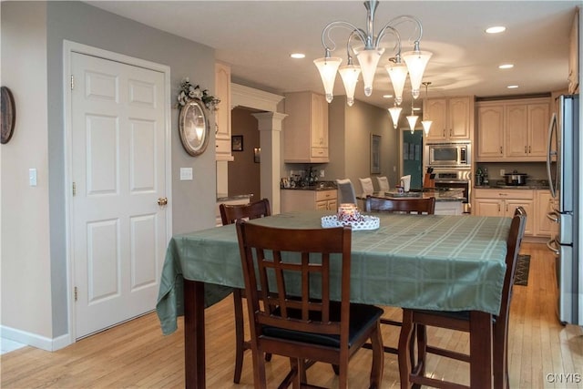 dining space with an inviting chandelier, light hardwood / wood-style flooring, and ornate columns