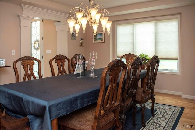 dining space with an inviting chandelier, wood-type flooring, and decorative columns