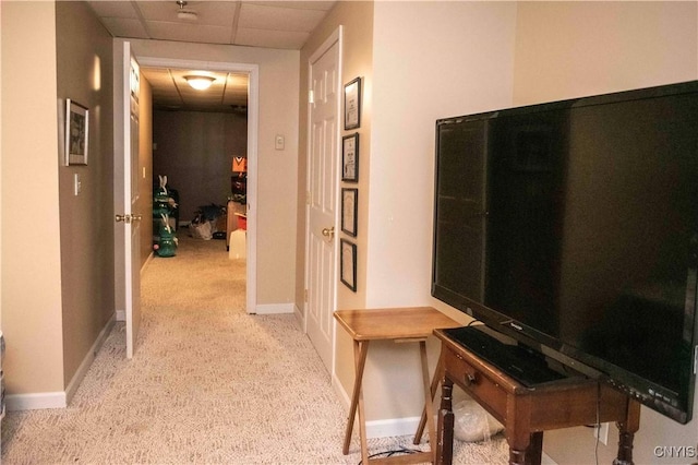 hall with a paneled ceiling and light colored carpet