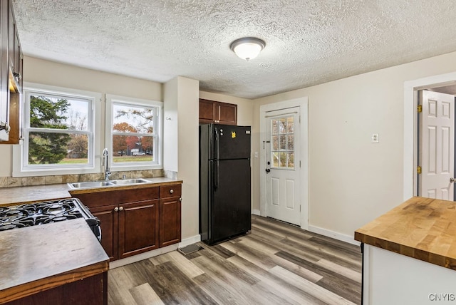 kitchen featuring light hardwood / wood-style floors, a textured ceiling, sink, and black fridge