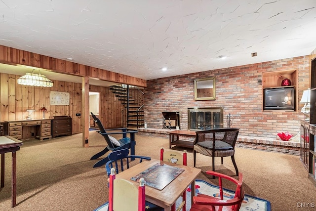 rec room featuring brick wall, wooden walls, a brick fireplace, and carpet