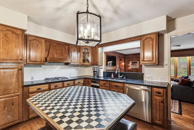 kitchen with dark wood-type flooring, sink, decorative light fixtures, premium range hood, and appliances with stainless steel finishes