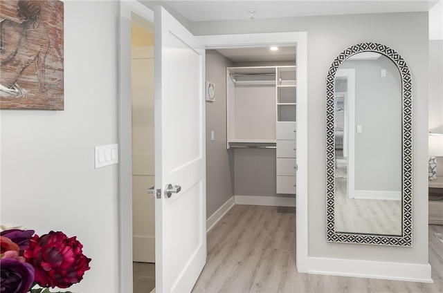 walk in closet with light hardwood / wood-style flooring