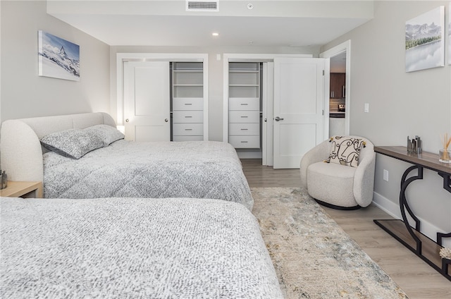 bedroom featuring two closets and light wood-type flooring