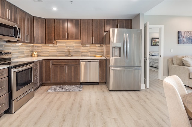 kitchen featuring sink, appliances with stainless steel finishes, light hardwood / wood-style flooring, and tasteful backsplash