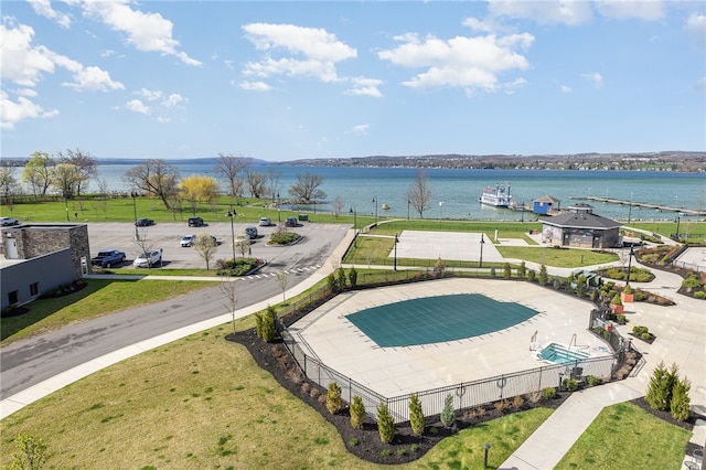 view of pool featuring a patio area, a water view, and a lawn