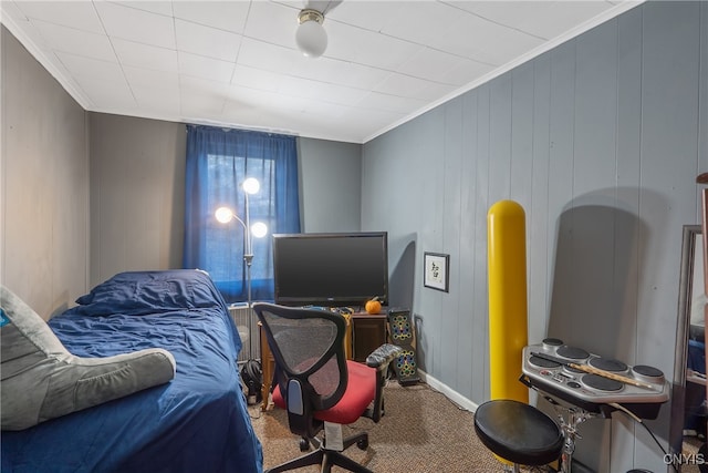 bedroom featuring ornamental molding, wooden walls, and carpet flooring