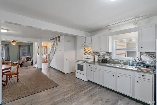 kitchen with decorative backsplash, electric range, white cabinetry, light hardwood / wood-style floors, and sink