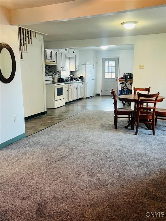 kitchen with light countertops, dark carpet, white cabinets, white appliances, and under cabinet range hood