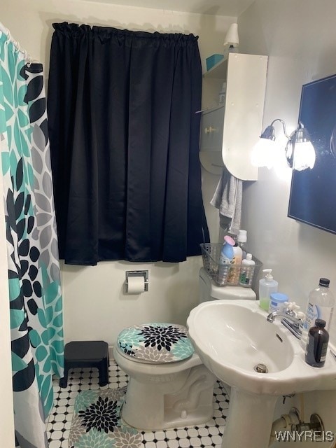 bathroom featuring tile patterned flooring, sink, toilet, and walk in shower