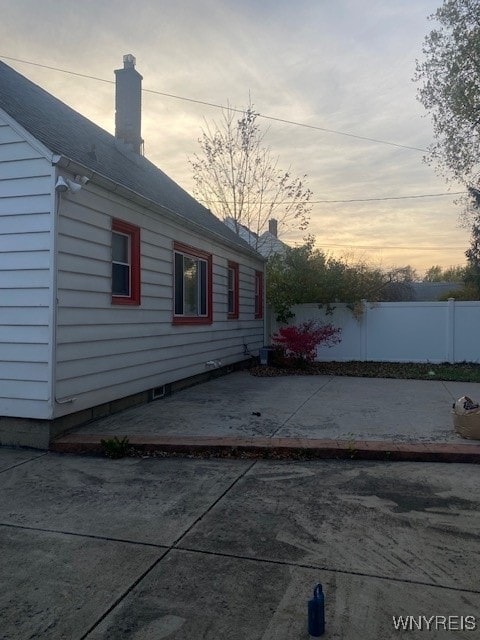 property exterior at dusk featuring a patio area