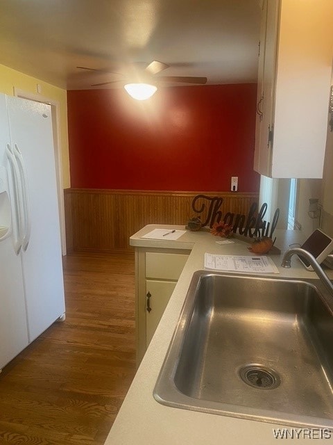 kitchen with white cabinets, wood-type flooring, white fridge with ice dispenser, and sink