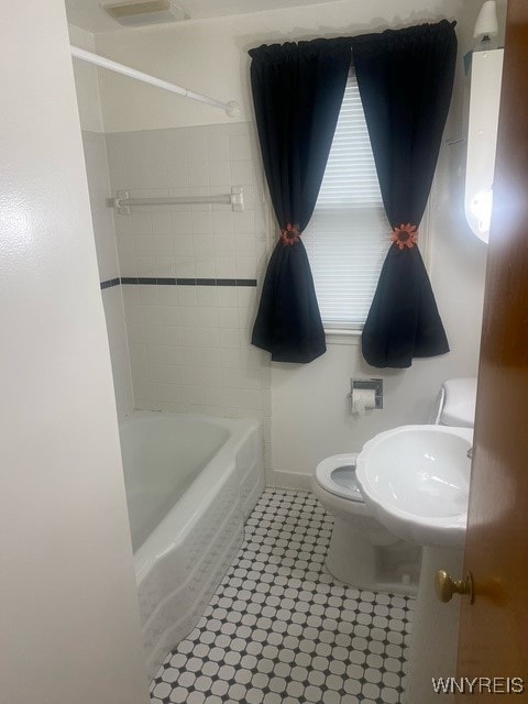 bathroom with tile patterned flooring, toilet, and tiled shower / bath