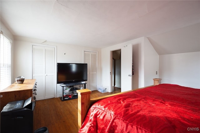 bedroom with hardwood / wood-style floors, multiple closets, and vaulted ceiling