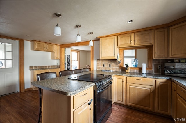 kitchen featuring a kitchen bar, black electric range, decorative light fixtures, and dark hardwood / wood-style floors