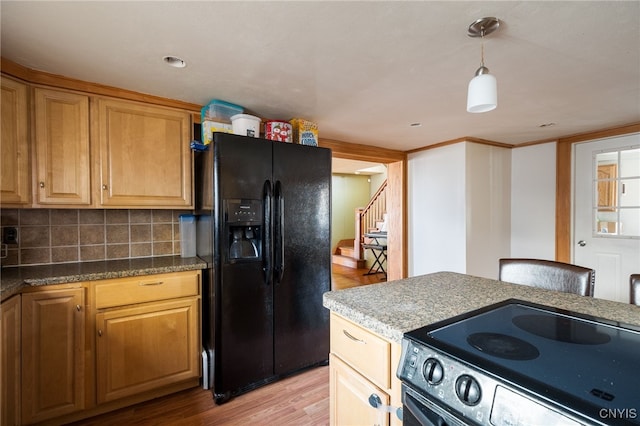 kitchen with light hardwood / wood-style flooring, black appliances, hanging light fixtures, and backsplash