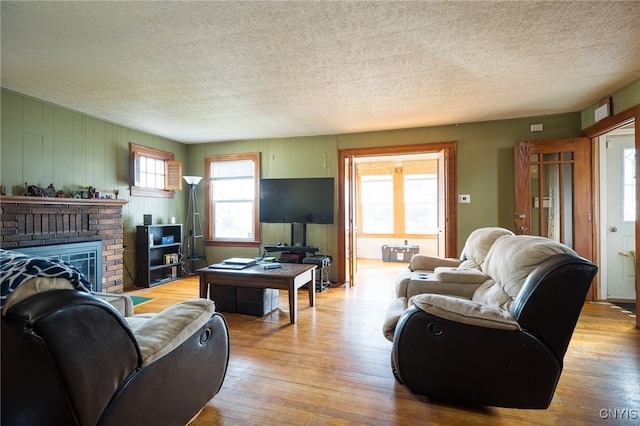 living room with light hardwood / wood-style floors, a textured ceiling, and a fireplace