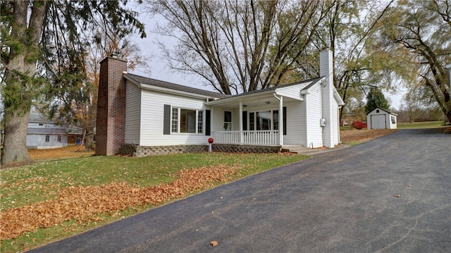 single story home with covered porch, a storage shed, and a front yard