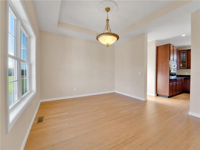 unfurnished room featuring a tray ceiling and light wood-type flooring