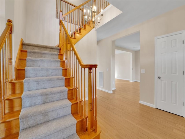 staircase featuring wood-type flooring and a chandelier