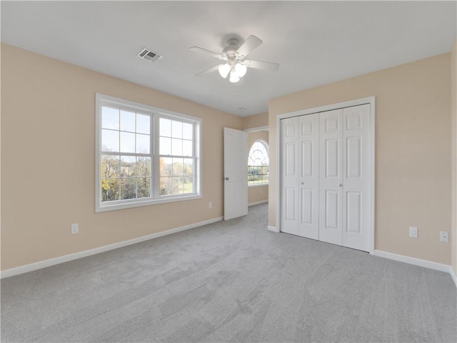 unfurnished bedroom featuring light carpet, ceiling fan, and a closet