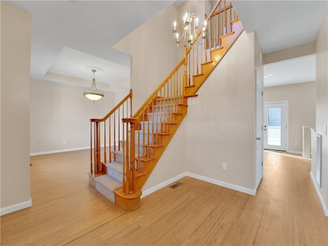 stairway with wood-type flooring and a tray ceiling