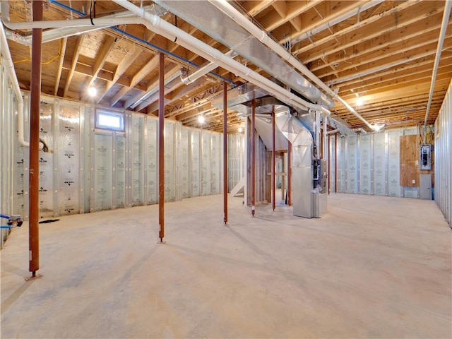 basement featuring electric panel and heating unit