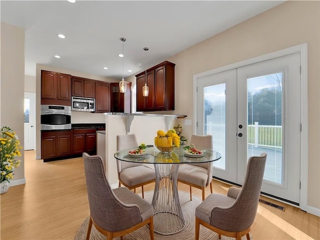 kitchen featuring hanging light fixtures, light hardwood / wood-style floors, french doors, and appliances with stainless steel finishes