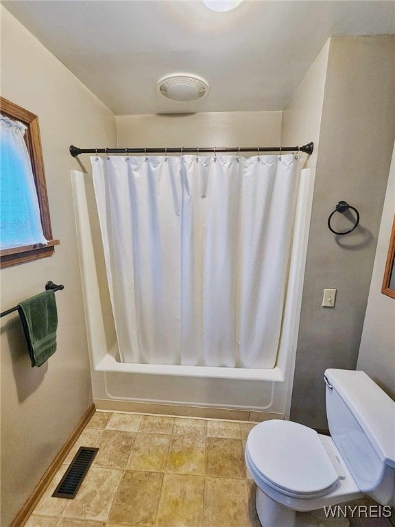 bathroom featuring toilet and shower / bath combination with curtain