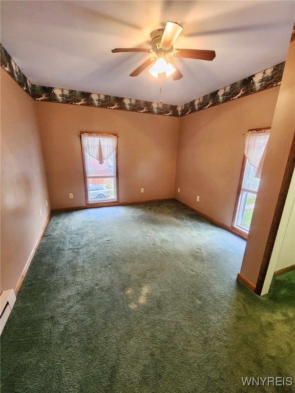 empty room featuring a wealth of natural light, dark carpet, and ceiling fan