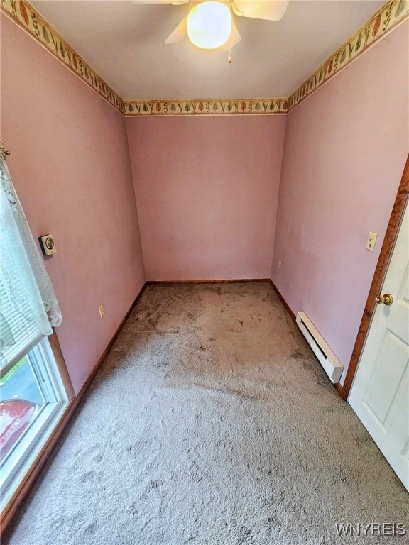 carpeted empty room featuring ceiling fan and baseboard heating