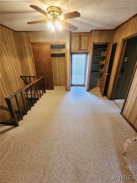 interior space with ceiling fan and wood walls